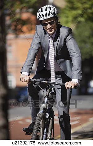 Stock Photography - Portrait of happy young businessman riding bicycle. Fotosearch