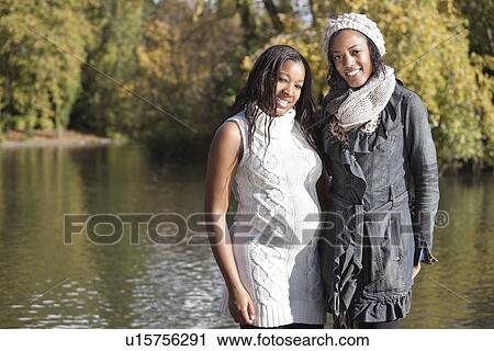 Portrait of happy young female friend embracing pregnant woman from behind View Large Photo Image Stock Image - Portrait of happy young female friend embracing pregnant woman from behind. Fotosearch
