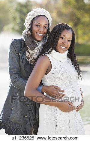 Portrait of happy young female friend embracing pregnant woman from behind View Large Photo Image Stock Photography - Portrait of happy young female friend embracing pregnant woman from behind. Fotosearch