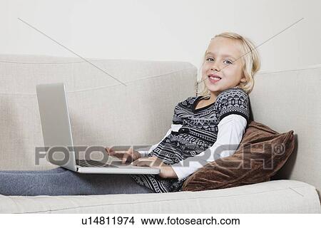 Portrait of happy young girl using laptop on sofa View Large Photo Image Picture - Portrait of happy young girl using laptop on sofa. Fotosearch