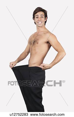 Portrait of happy young man wearing oversized pants against gray background View Large Photo Image Stock Image - Portrait of happy young man wearing oversized pants against gray background. Fotosearch