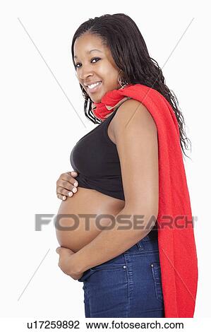 Stock Image - Portrait of happy young pregnant woman wearing superhero cape over white background. Fotosearch