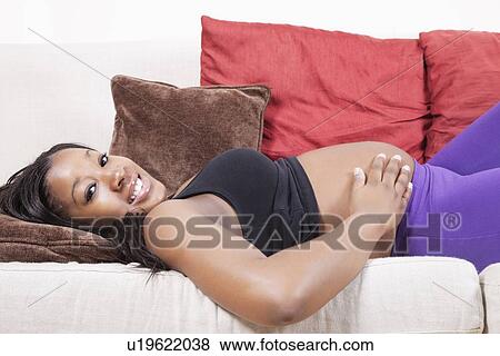 Stock Photo - Portrait of happy young pregnant woman resting on sofa. Fotosearch