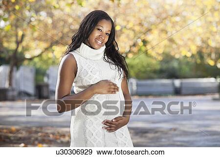 Portrait of happy young pregnant woman in park View Large Photo Image Stock Photo - Portrait of happy young pregnant woman in park. Fotosearch