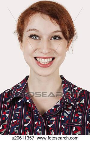 Portrait of happy young woman in shirt against gray background View Large Photo Image Stock Photo - Portrait of happy young woman in shirt against gray background. Fotosearch
