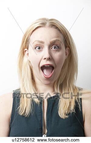 Stock Image - Portrait of shocked young woman screaming against white background. Fotosearch