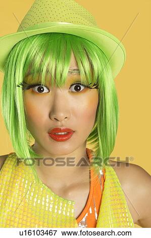 Stock Photo - Portrait of shocked young woman with green hair against yellow background. Fotosearch
