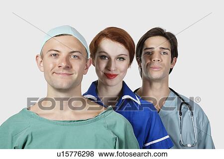 Stock Photo - Portrait of three medical practitioners smiling together against gray background. Fotosearch