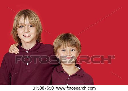 Portrait of two happy brothers against red background View Large Photo Image Stock Image - Portrait of two happy brothers against red background. Fotosearch