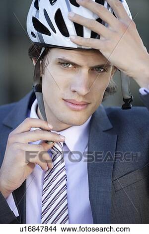 Picture - Portrait of young businessman adjusting helmet. Fotosearch