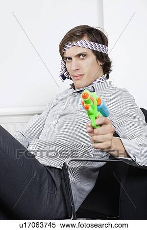 Portrait of young businessman holding toy gun View Large Photo Image Stock Photography - Portrait of young businessman holding toy gun. Fotosearch