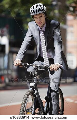 Picture - Portrait of young businessman riding bicycle. Fotosearch