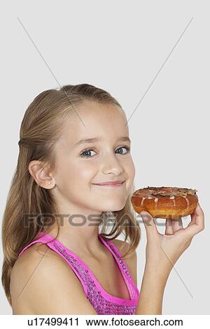 Portrait of young girl holding donut against gray background View Large Photo Image Stock Image - Portrait of young girl holding donut against gray background. Fotosearch
