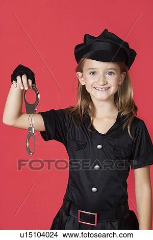Portrait of young girl in police costume holding handcuffs against red background View Large Photo Image Picture - Portrait of young girl in police costume holding handcuffs against red background. Fotosearch
