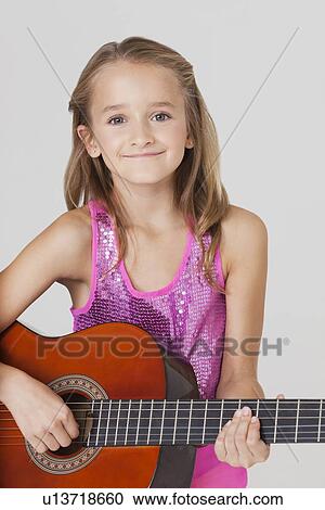 Portrait of young girl playing guitar against gray background View Large Photo Image Stock Image - Portrait of young girl playing guitar against gray background. Fotosearch