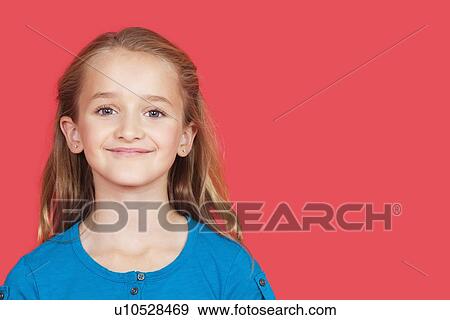 Stock Photo - Portrait of young girl smiling against red background. Fotosearch