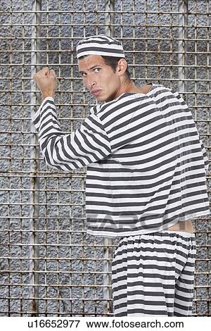 Portrait of young male prisoner in uniform standing against prison cell View Large Photo Image Stock Photo - Portrait of young male prisoner in uniform standing against prison cell. Fotosearch
