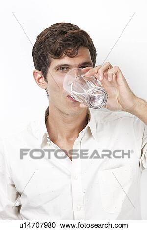 Portrait of young man drinking water against white background View Large Photo Image Stock Image - Portrait of young man drinking water against white background. Fotosearch