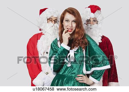 Portrait of young men in Santa costume standing with woman against gray background View Large Photo Image Stock Photo - Portrait of young men in Santa costume standing with woman against gray background. Fotosearch