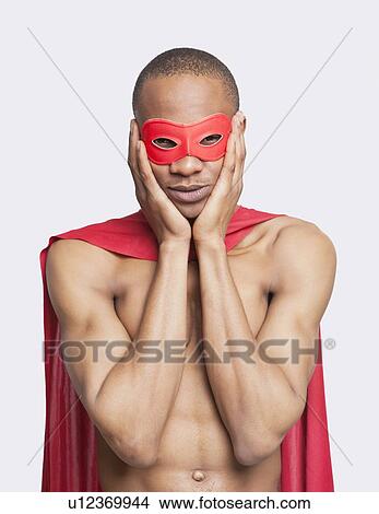 Portrait of young shirtless man in superhero costume with hands on face against gray background View Large Photo Image Picture - Portrait of young shirtless man in superhero costume with hands on face against gray background. Fotosearch