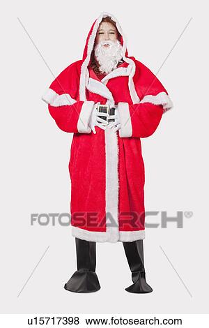 Portrait of young woman in Santa costume standing against gray background View Large Photo Image Stock Photo - Portrait of young woman in Santa costume standing against gray background. Fotosearch