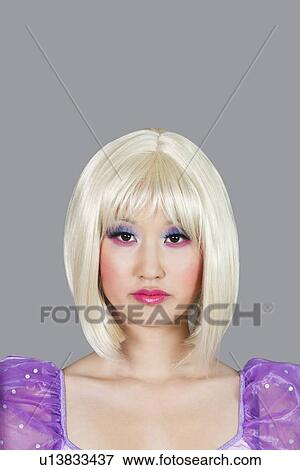 Stock Photo - Portrait of young woman with blond hair against gray background. Fotosearch