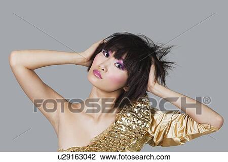 Portrait of young woman with hands in hair over gray background View Large Photo Image Stock Image - Portrait of young woman with hands in hair over gray background. Fotosearch