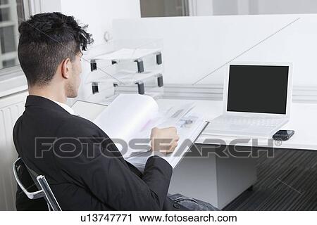 Rear view of young businessman working at office View Large Photo Image Stock Image - Rear view of young businessman working at office. Fotosearch
