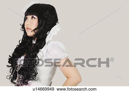 Side view of thoughtful young woman in doll costume looking away against gray background View Large Photo Image Stock Photo - Side view of thoughtful young woman in doll costume looking away against gray background. Fotosearch