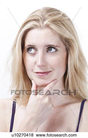 Stock Photo - Thoughtful young woman with hand on chin looking away against white background. Fotosearch
