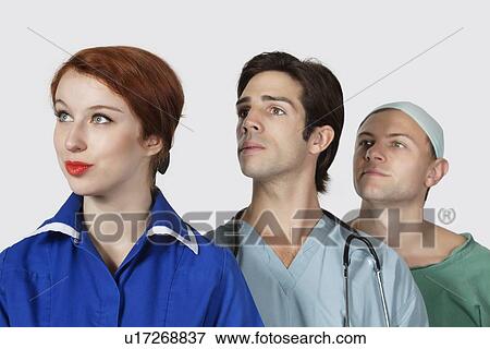 Three medical practitioners looking away against gray background View Large Photo Image Stock Photo - Three medical practitioners looking away against gray background. Fotosearch