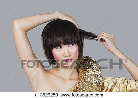 Stock Image - Woman in golden costume playing with hair over gray background. Fotosearch