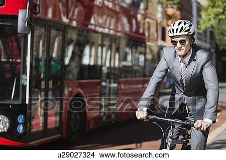 Young businessman riding bicycle by bus on street View Large Photo Image Picture - Young businessman riding bicycle by bus on street. Fotosearch