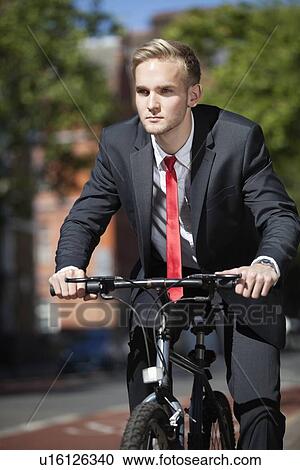 Young businessman riding bicycle on street View Large Photo Image Stock Image - Young businessman riding bicycle on street. Fotosearch