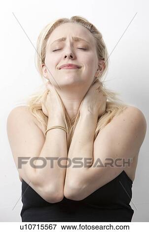 Stock Photo - Young Caucasian woman suffering from neckache standing against white background. Fotosearch