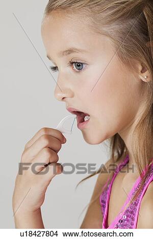 Young girl flossing teeth against gray background View Large Photo Image Picture - Young girl flossing teeth against gray background. Fotosearch