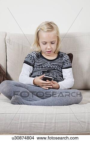 Young girl reading text message on sofa View Large Photo Image Picture - Young girl reading text message on sofa. Fotosearch