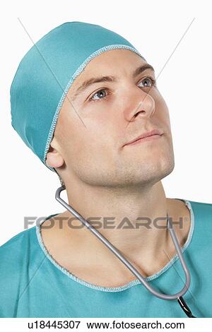 Young male surgeon in scrubs looking away against white background View Large Photo Image Stock Photo - Young male surgeon in scrubs looking away against white background. Fotosearch