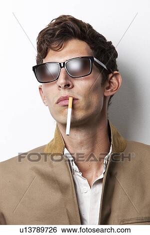 Young man in sunglasses smoking cigarette against white background View Large Photo Image Stock Photograph - Young man in sunglasses smoking cigarette against white background. Fotosearch