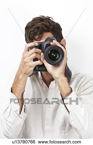 Young man taking photograph with retro style camera against white background View Large Photo Image Stock Photograph - Young man taking photograph with retro style camera against white background. Fotosearch