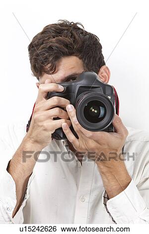 Stock Photograph - Young man taking photograph with vintage camera against white background. Fotosearch