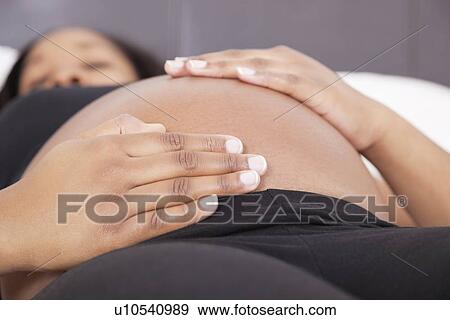 Young pregnant woman relaxing with hands on stomach View Large Photo Image Stock Photo - Young pregnant woman relaxing with hands on stomach. Fotosearch
