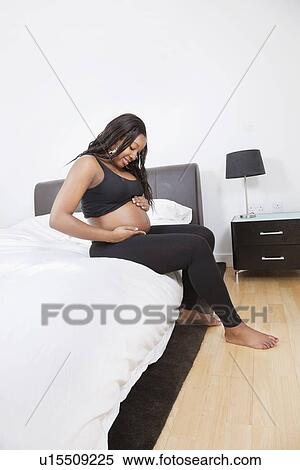 Young pregnant woman touching her belly in bed View Large Photo Image Stock Photography - Young pregnant woman touching her belly in bed. Fotosearch