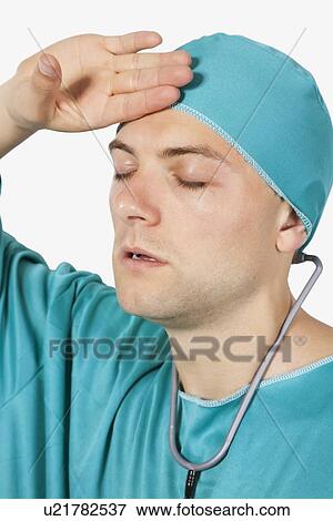 Young tired surgeon wearing scrubs against white background View Large Photo Image Stock Photo - Young tired surgeon wearing scrubs against white background. Fotosearch