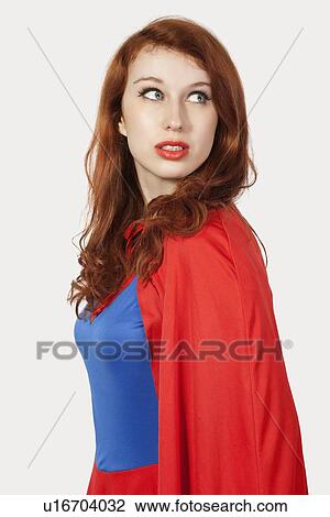 Young woman in superhero costume looking away against gray background View Large Photo Image Stock Image - Young woman in superhero costume looking away against gray background. Fotosearch