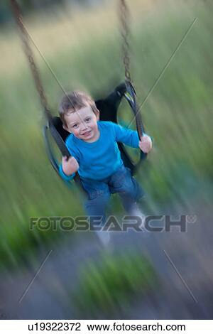 Stock Image - Blurred view of boy swinging. Fotosearch
