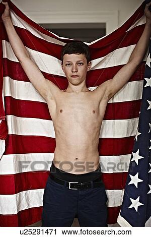 Stock Image - Boy holding American flag indoors. Fotosearch