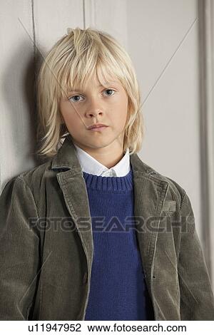 Stock Image - Boy leaning against door. Fotosearch