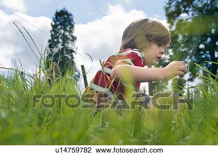 Stock Image - Boy playing in grassy field. Fotosearch