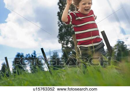Stock Image - Boy playing in grassy field. Fotosearch